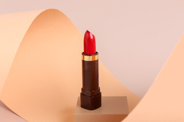 Decorative podium with beautiful red lipstick on beige background