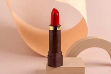 Decorative podium with beautiful red lipstick on beige background