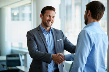 Happy young businessman welcoming a new colleague with a handshake