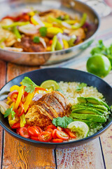 chicken fajita bowl with pan roasted chicken, sauteed red and yellow bell pepper, sliced avocado, fresh lime juice on a bed of cauliflower rice