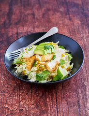 fish taco bowl with shredded cabbage, sliced avocado, fresh cilantro, lime juice and sauteed fish