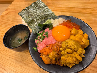 Japanese food Uni Sashimi and fried egg in bowl on wooden table