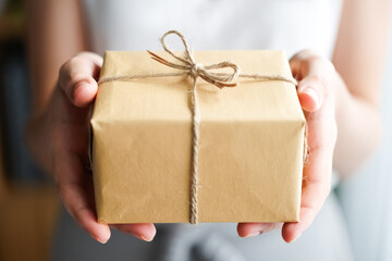 Person is holding a brown box with a bow on it