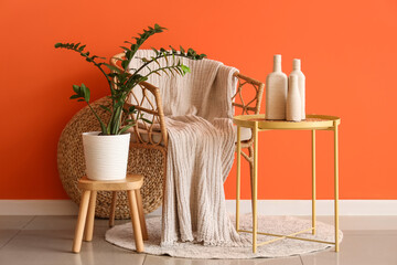 Chair, table and houseplant near orange wall in interior of room