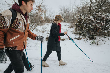 Friends explore a snowy wilderness on a refreshing winter day trek, using trekking poles for the...