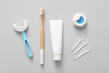 Different toothbrushes with dental floss, toothpicks and tube of paste on grey background