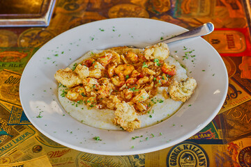 shrimp and grits made with a tasso ham gravy and topped with fried oysters