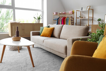 Interior of living room with clothes rack, sofa and table