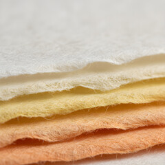 Close up of colorful textured handmade paper sheets in pastel shades stacked in layers