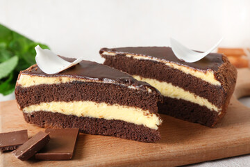 Wooden board with pieces of sweet chocolate cake on white background