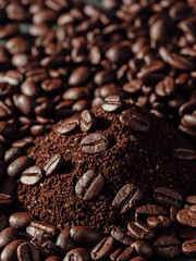 Ground Coffee Pile Surrounded by Whole Coffee Beans on Dark Surface