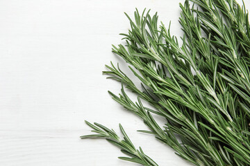 Fototapeta premium Fresh rosemary twigs on white wooden background