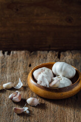 Fresh Garlic Bulbs and Cloves in Rustic Wooden Bowl on Table