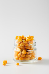 Fresh Yellow Corn Kernels in a Glass Jar on a White Background