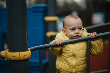 A young child explores a park playground, dressed warmly, embodying curiosity and playfulness.