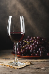 Elegant Red Wine Glass with Grapes on Wooden Table Background