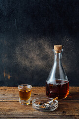 Glass Carafe and Whiskey Glass with Cigarettes on Wooden Table