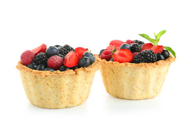 Sweet tartlets with different fresh berries and mint on white background