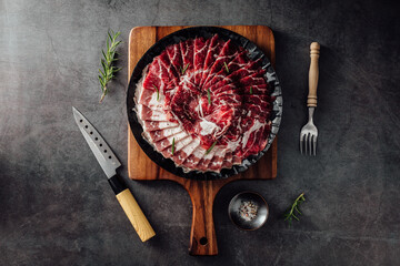 Freshly Sliced Raw Meat on Wooden Board with Knife and Fork