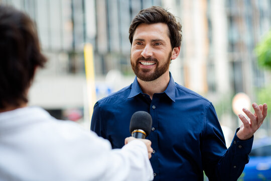Confident male professional being interviewed outdoors with urban background conveying success and positive demeanor