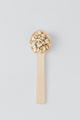Wooden Spoon with Dried White Puffed Corn on Light Background