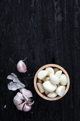 Fresh Garlic Cloves in Wooden Bowl on Dark Wooden Surface