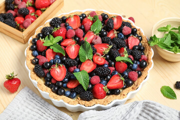 Sweet tart with different fresh berries and mint on wooden background, closeup