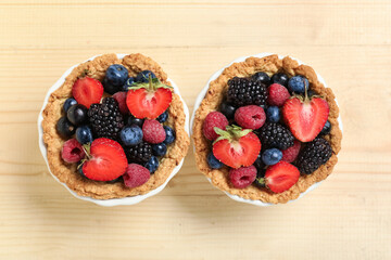 Sweet tartlets with different fresh berries on wooden background