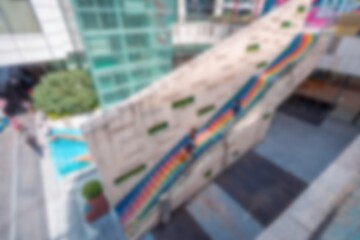 Blurry abstract view of a shopping mall in Shenzhen, China with a rainbow pattern on a wall in the background.