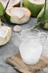 Fresh Coconut Water in Glass Jug Surrounded by Green Coconuts