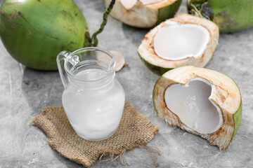 Fresh Coconut Water with Green Coconuts on Rustic Surface