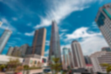 Obraz premium An abstract view of skyscrapers in a shopping mall against a bright blue sky with white clouds.