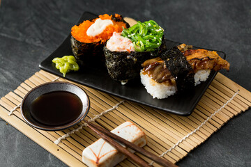 Assorted Sushi Rolls with Wasabi and Soy Sauce on a Black Plate