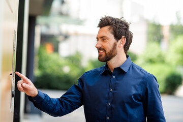 Smiling businessman outdoors interacting with modern office technology in an urban setting