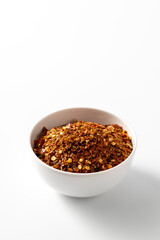 Spicy Red Pepper Flakes in White Bowl on Minimalist Background