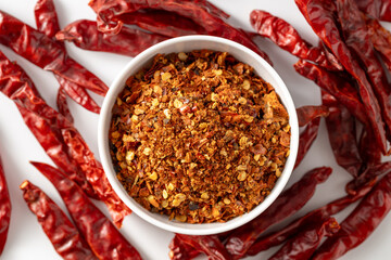 Spicy Red Chili Flakes in Bowl Surrounded by Dried Red Peppers