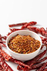 Spicy Red Chili Powder in White Bowl Surrounded by Dried Peppers