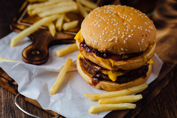 Juicy Cheeseburger with BBQ Sauce and Crispy French Fries on Wood