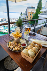 eating fried squid calamari with a sea view from balcony in croatia with drinks