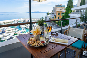 eating fried squid calamari with a sea view from balcony in croatia with drinks