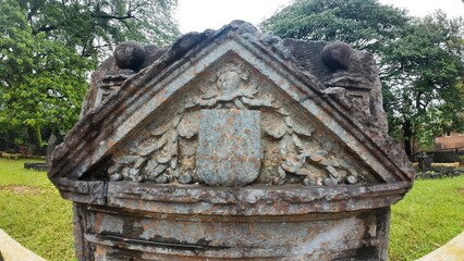  Historic gravestone with intricate carvings and engravings displayed in the open area of the Chapel of St. Catherine, Old Goa
