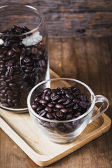 Glass Container and Cup Filled with Roasted Coffee Beans on Wood
