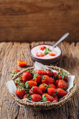 Fresh Red Strawberries in Woven Basket with Yogurt on Wooden Table