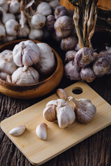 Fresh Garlic Cloves on Wooden Board with Whole Bulbs in Background