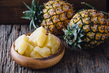 Fresh Pineapple Pieces in Wooden Bowl with Whole Pineapples Nearby