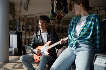 A man plays electric guitar near a woman enjoying the music