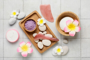 Obraz na płótnie Canvas Beautiful spa composition with tray, stones, plumeria flowers and bowl with sea salt on beige tile background, closeup
