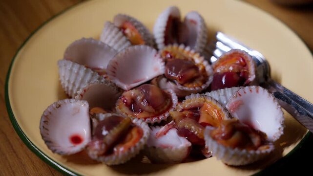 Close-up of fresh cockles served in a creamy-toned bowl, showcasing their natural textures and rich, briny appeal. Perfect for seafood-themed content, culinary videos, or restaurant promotions.