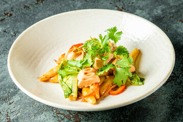 Stir-fried tofu with lotus root, bok choy, and bell pepper served on a white plate. Colorful...