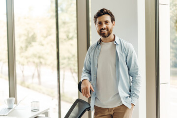 Confident businessman smiling in modern office by window